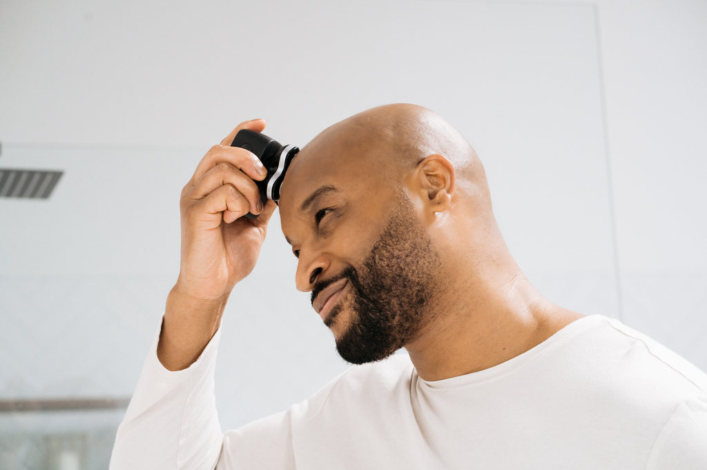 bald man shaving with rotary shaver